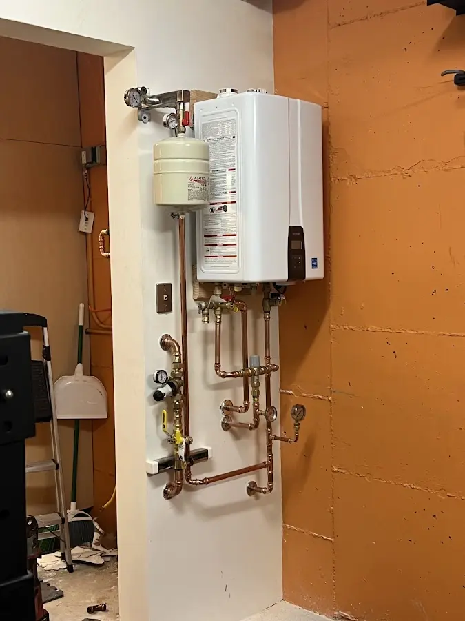 Plumbing technician inspecting water heater connections in Indialantic